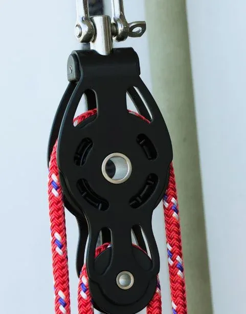 Poulie noire et cordage rouge sur un voilier